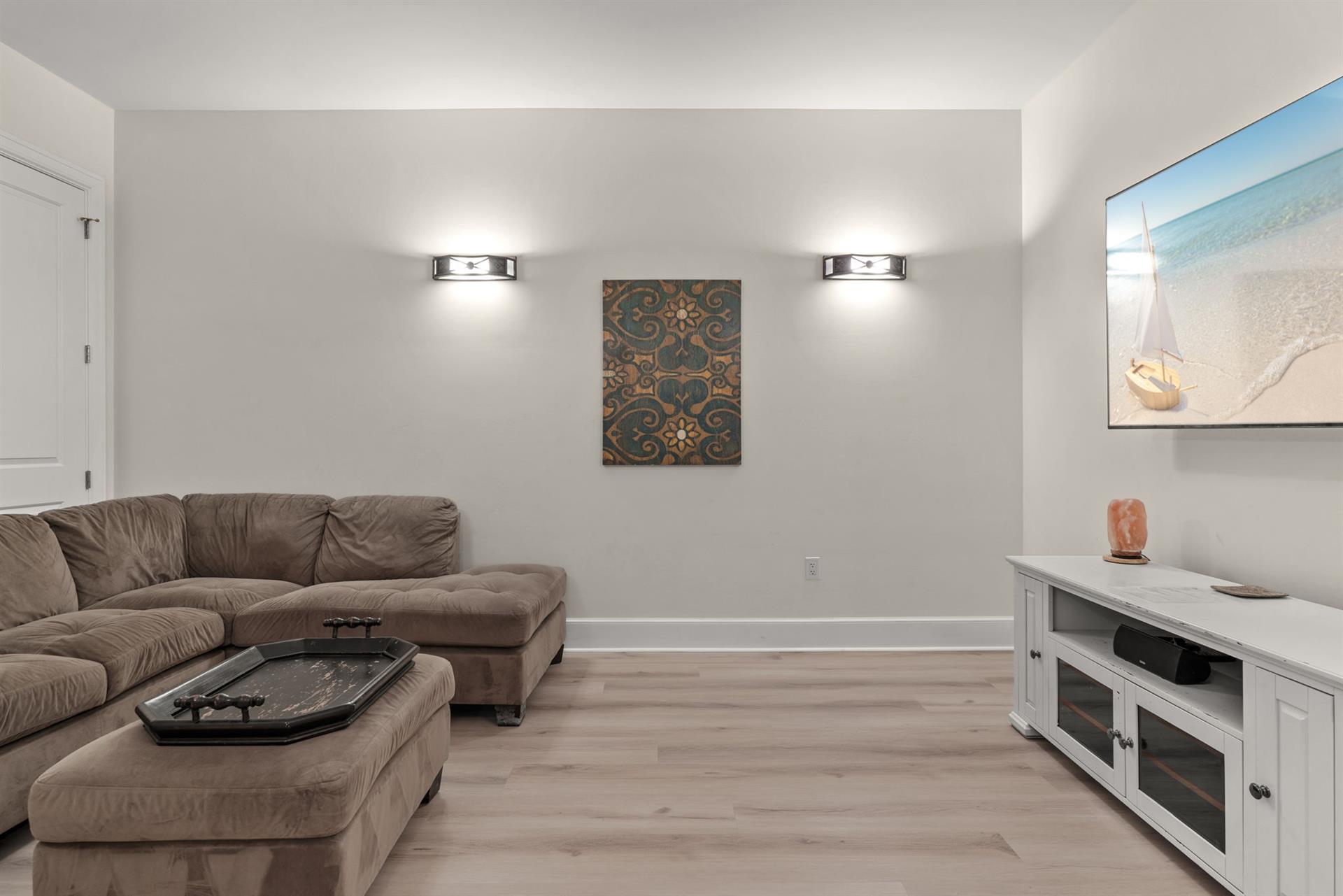 Sink into plush seating and unwind in your private tv room, complete with modern entertainment setup and coastal artwork.