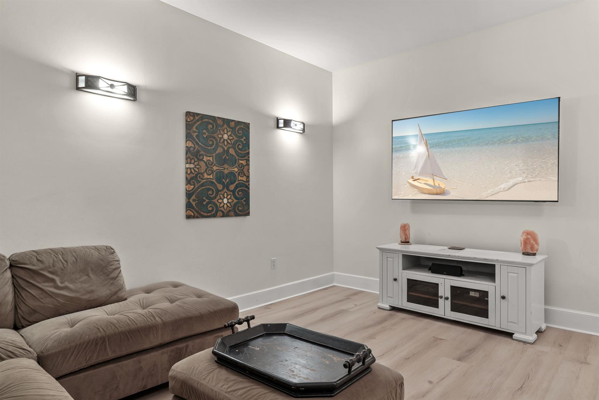 Sink into plush seating and enjoy your favorite movies or shows on the large TV, with coastal artwork creating a serene atmosphere.