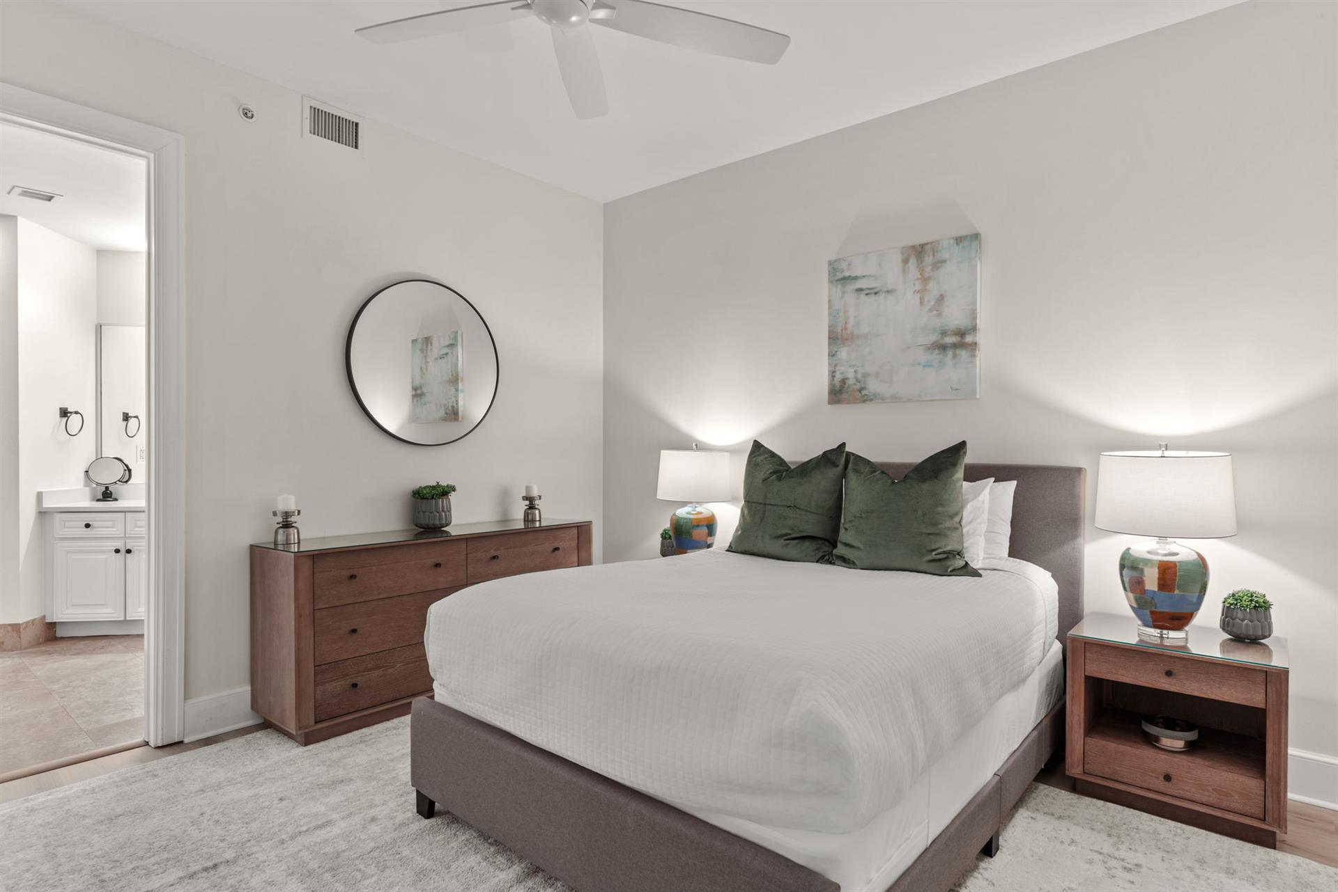 Your peaceful bedroom retreat features a plush bed with forest green pillows and warm wood furnishings for restful nights.