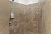 Step into your luxurious shower featuring elegant stone walls, rainfall showerhead, for a spalike experience.