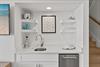 Stylish open shelving complements the sleek wet bar.