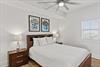 This serene queen bedroom features plush bedding and a gentle ceiling fan.,