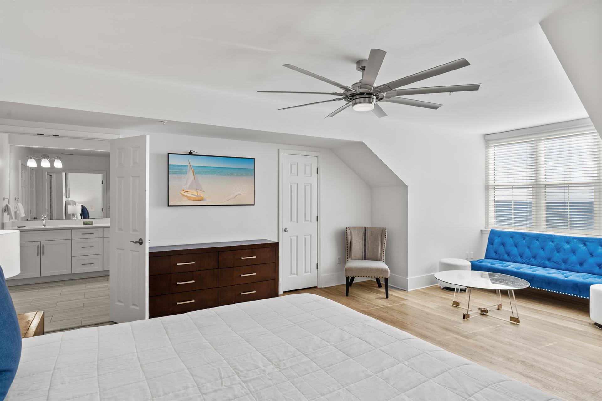 The spacious king master suite with a vibrant blue sofa and an ensuite bathroom.