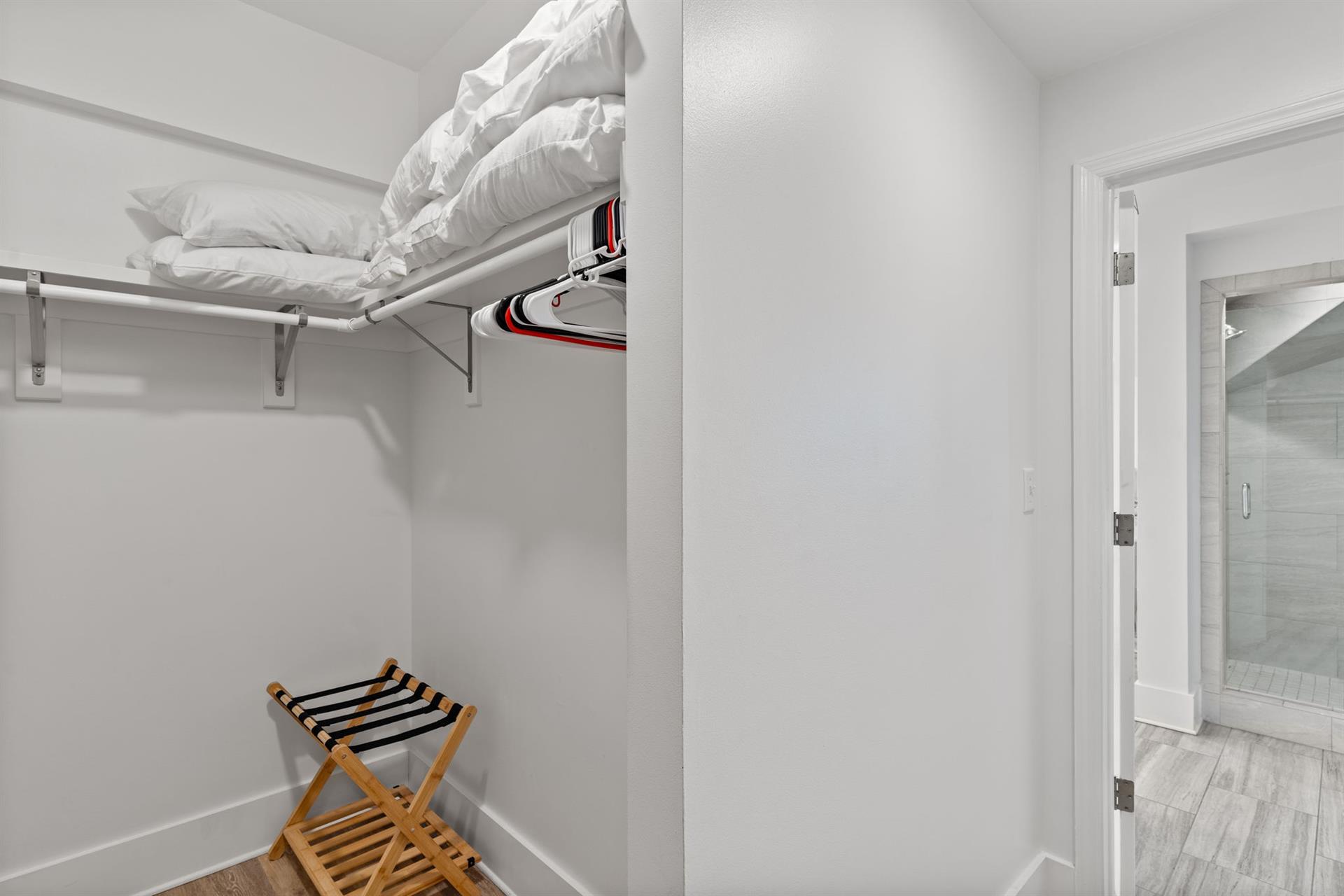 The walkin closet features shelving, hanging space, and a  luggage rack.