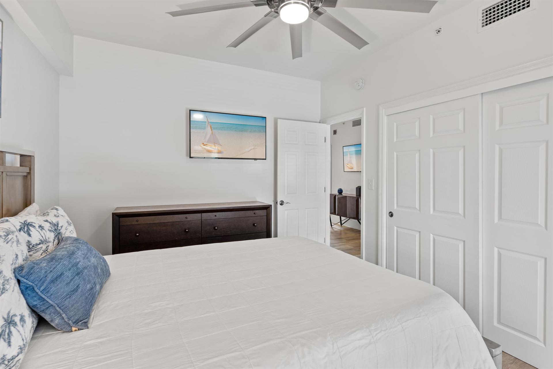 The 2nd floor queen bedroom with coastal charm and a wall mounted TV.
