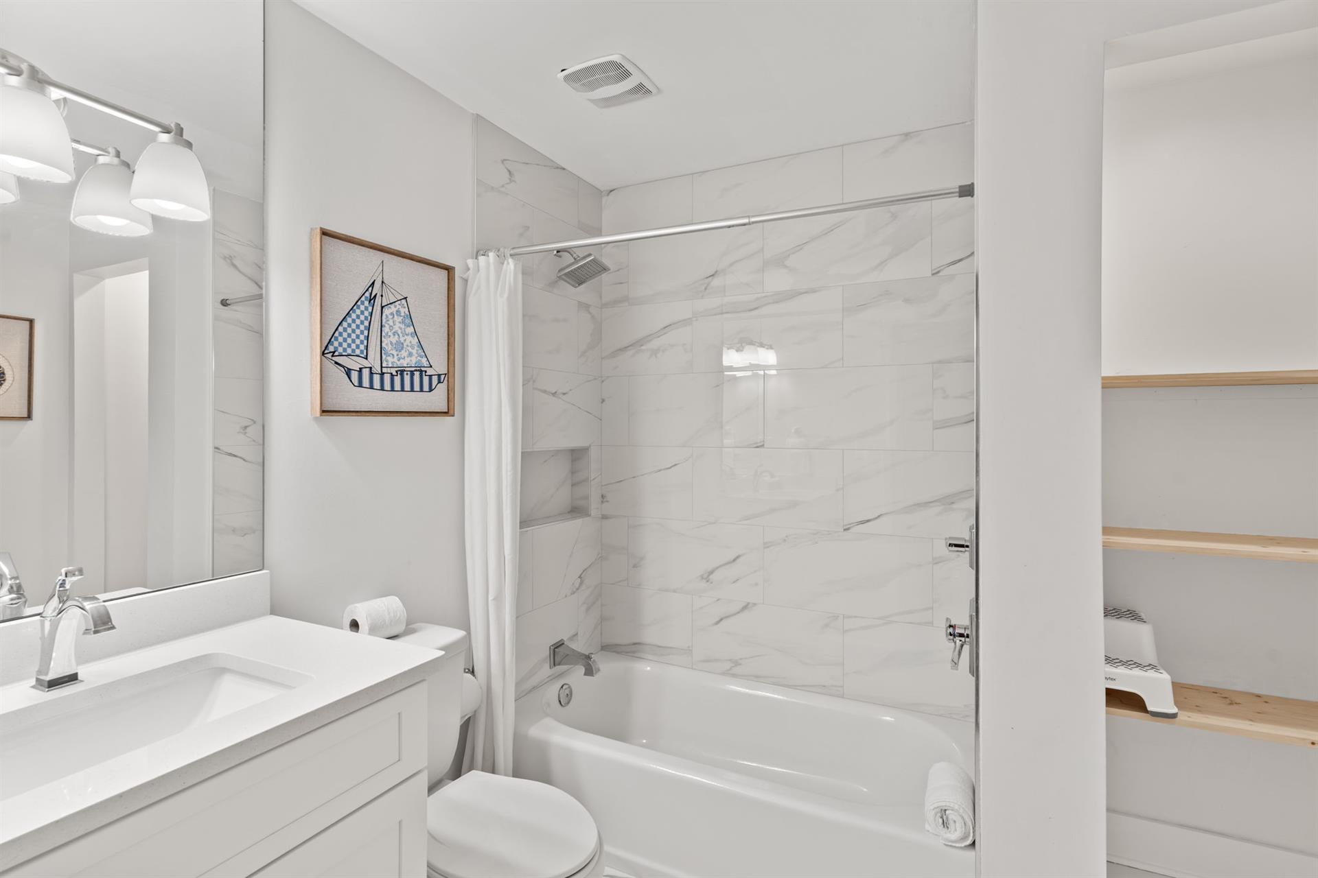 The 2nd floor shared bathroom featuring elegant marblelook tiles and a soaking tub.