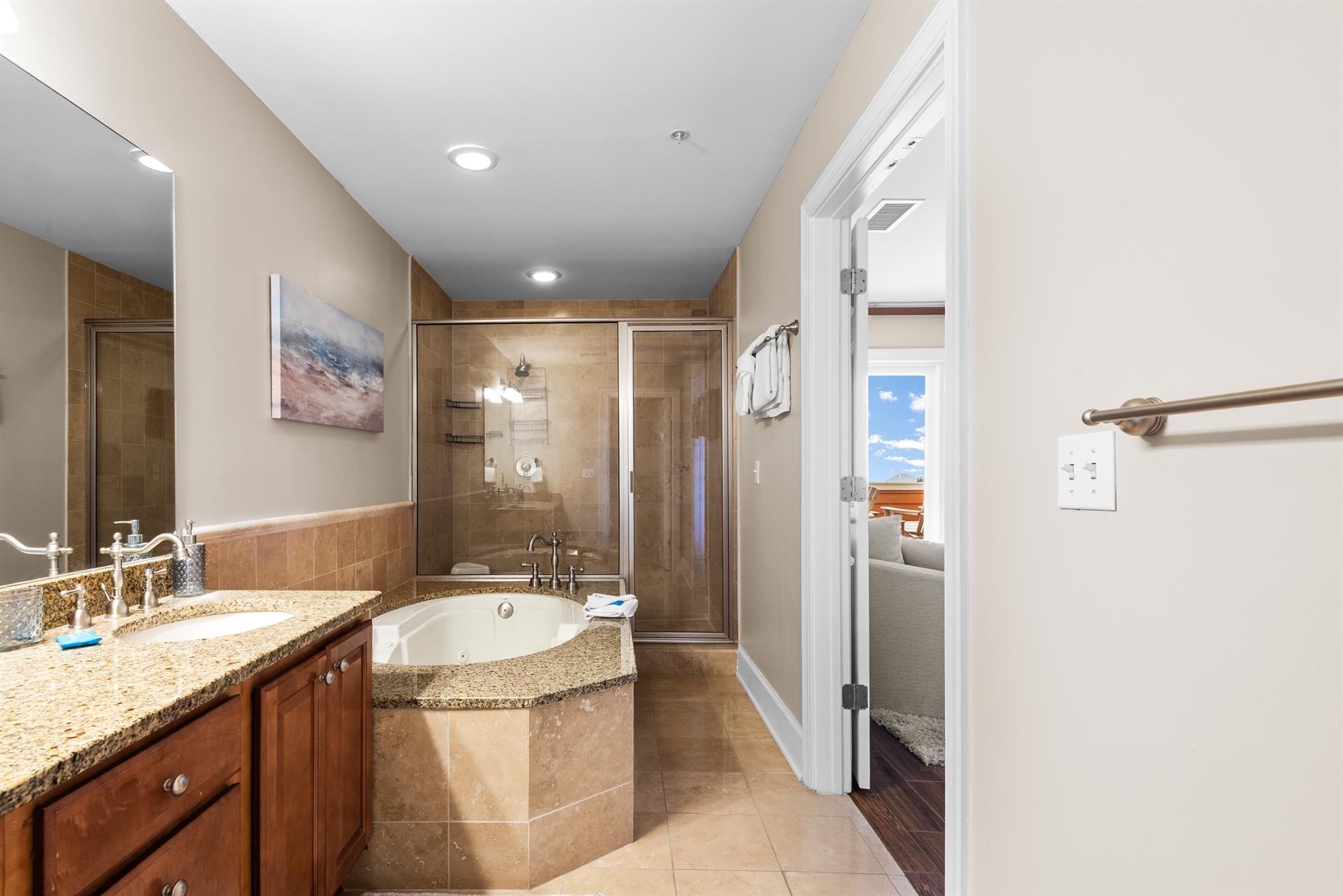Unwind in the luxurious ensuite featuring a soaking tub, granite countertops, and elegant tile finishes—your personal spa retreat after a long beach day.