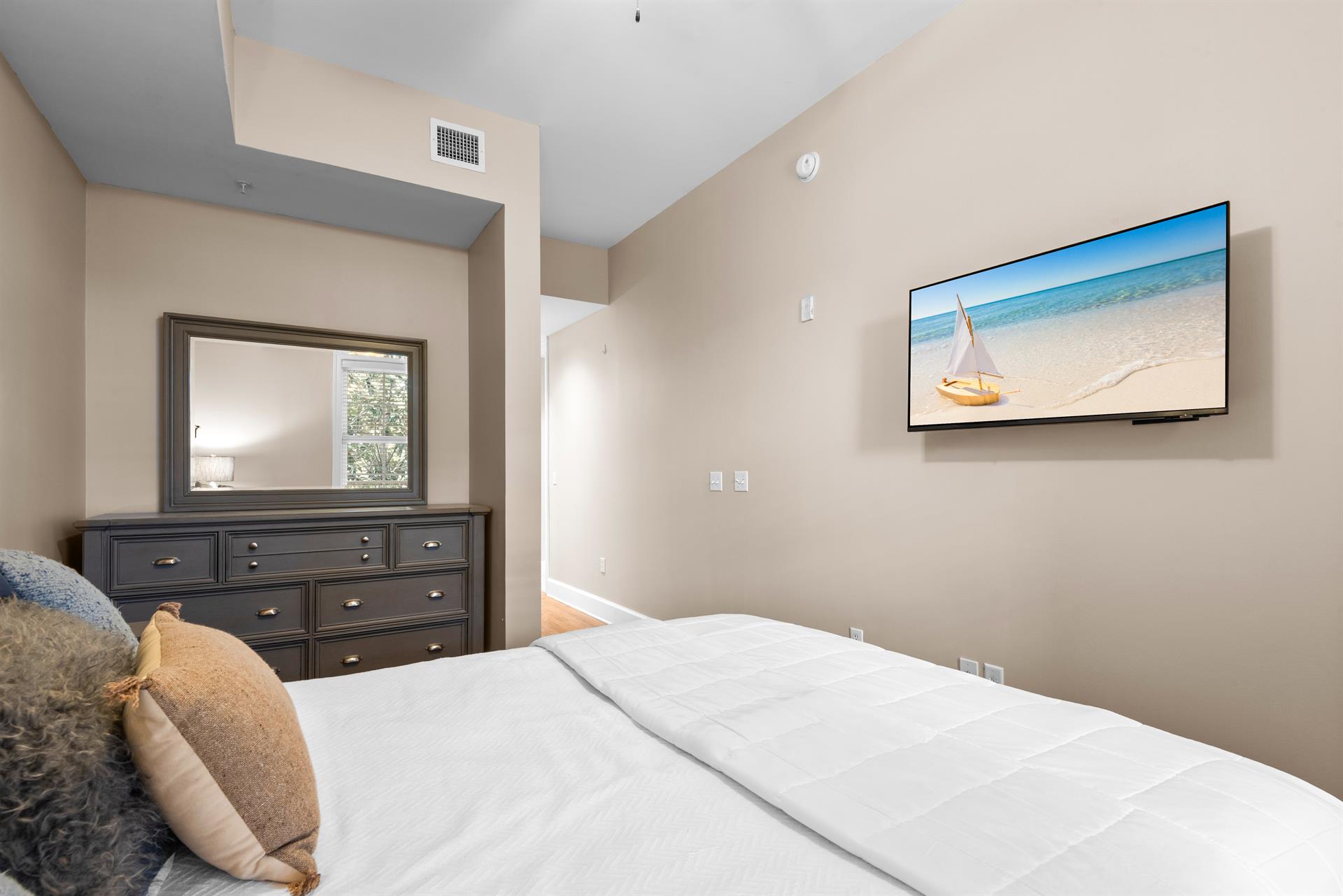 Sink into this plush queen bed while enjoying entertainment on the wallmounted TV, with dresser storage for all your belongings.