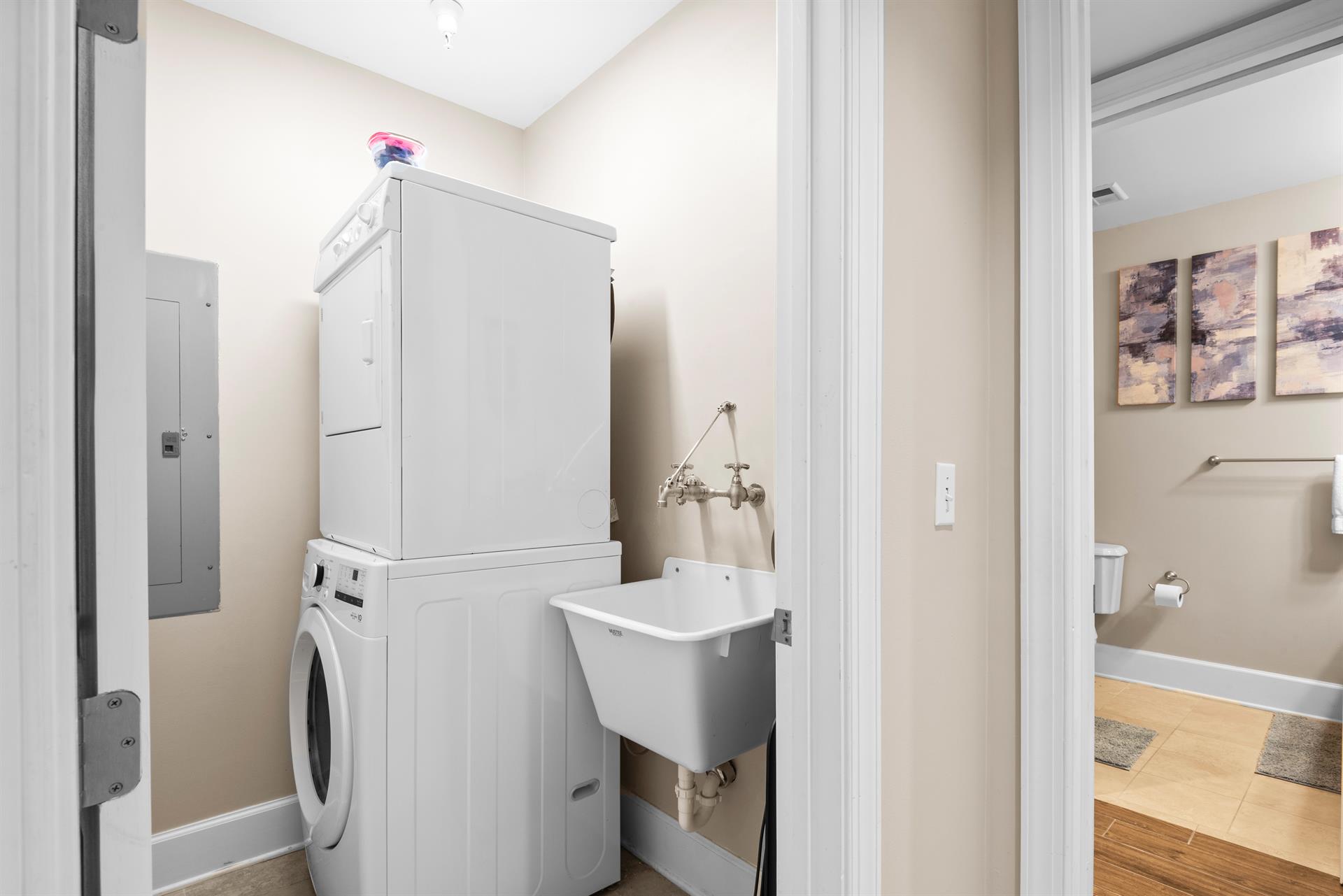 Dedicated laundry space features a stacked washerdryer and utility sink, making longer stays effortless and convenient.