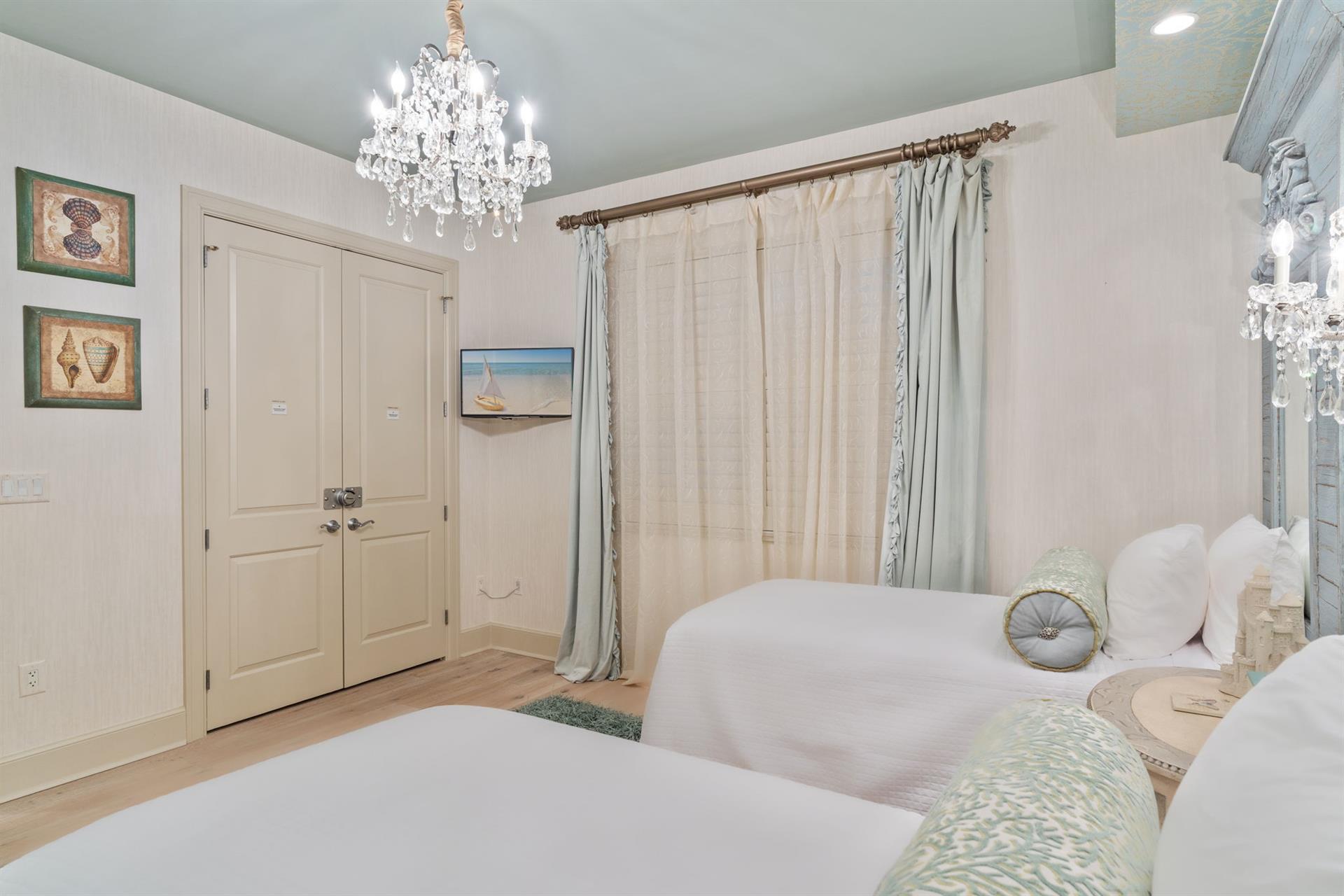 Elegant twin bedroom with crystal chandeliers and soft linens for restful nights.