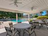 The covered patio offers cool shade and poolside dining with ceiling fans