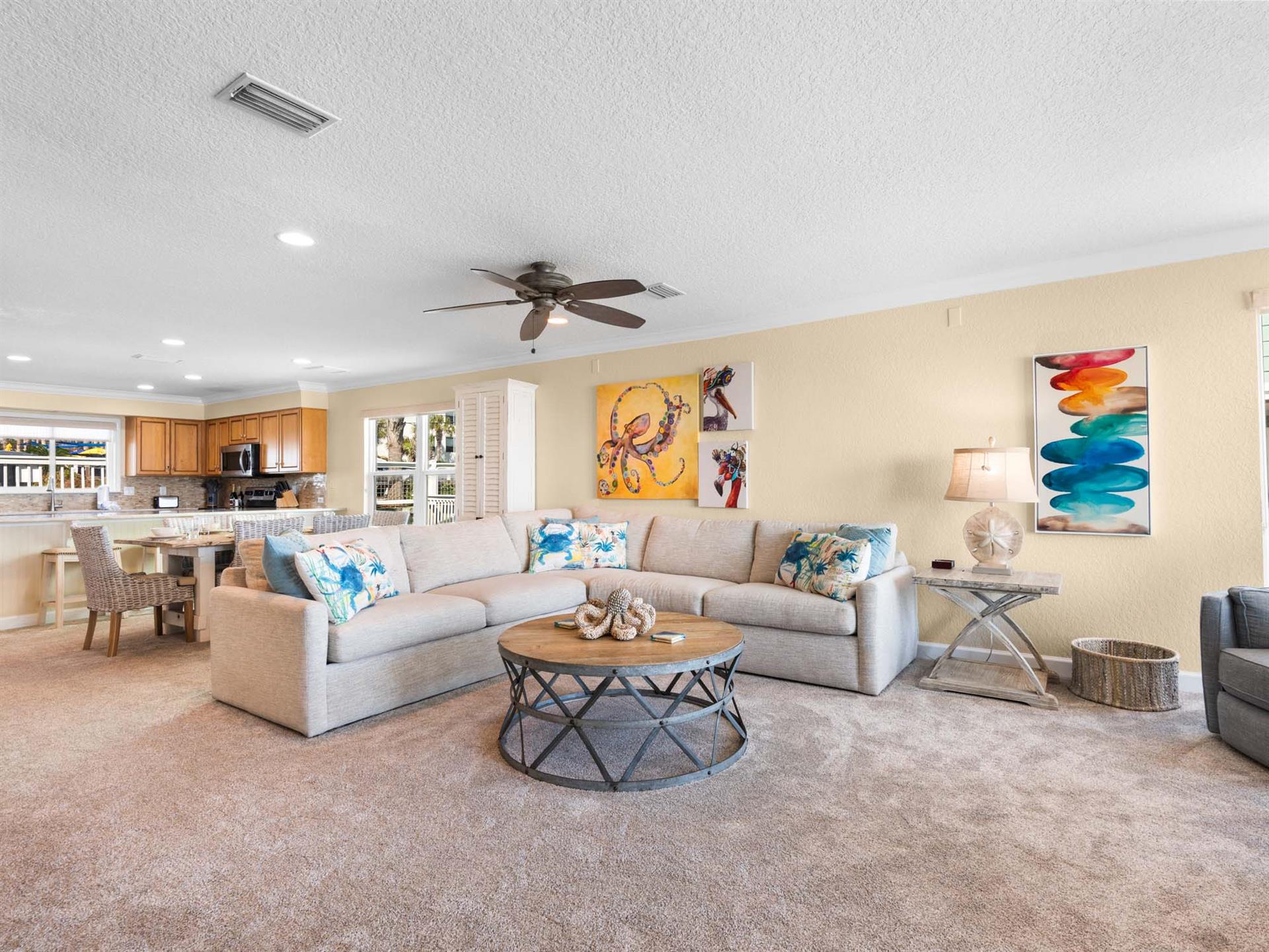 Unwind in the living area with plush sectional seating, vibrant coastal art, and an openconcept flow to the fully equipped kitchen.