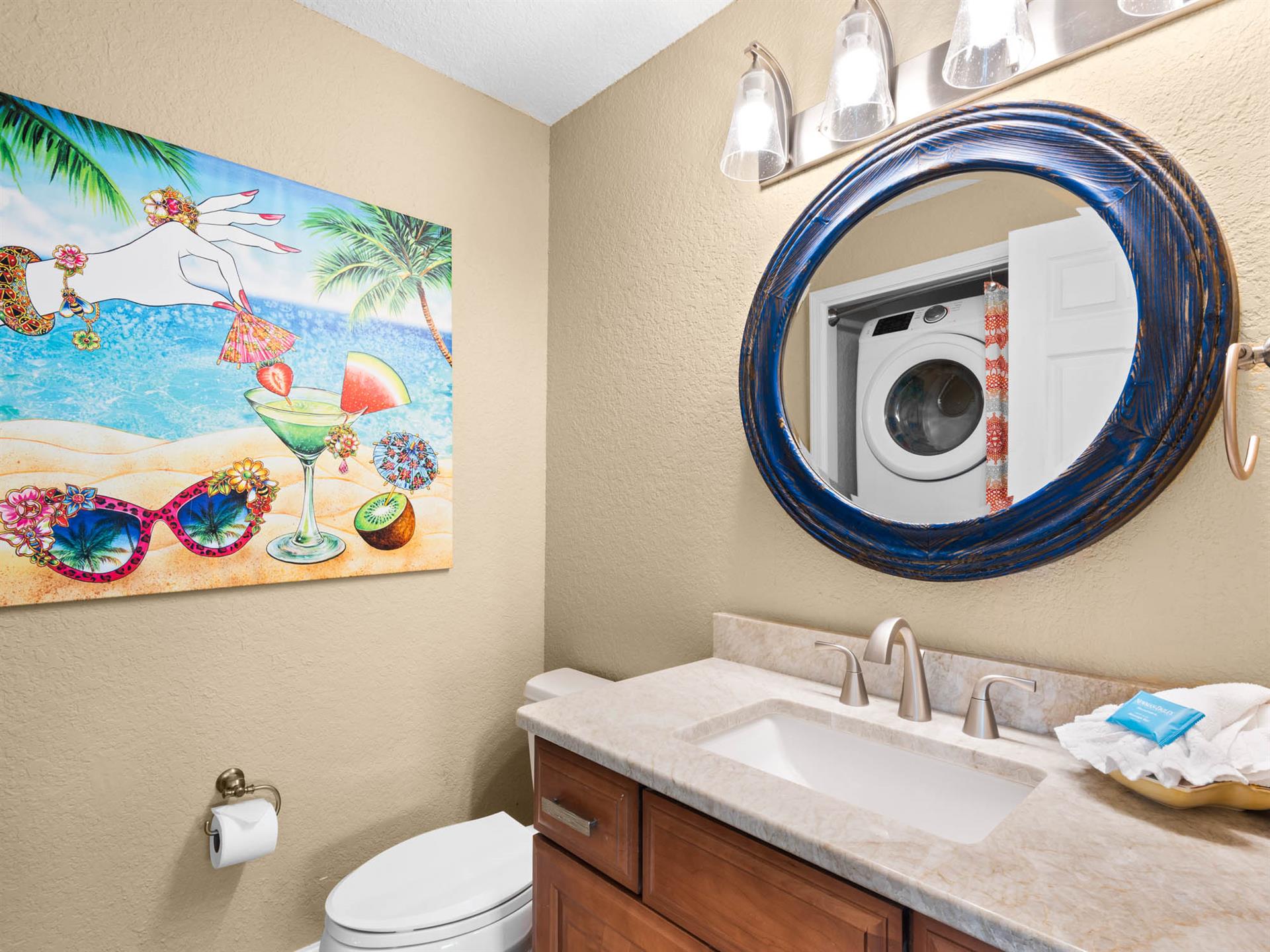 Bathroom 3  The coastalthemed bathroom features a tropical mural, elegant round mirror, and convenient washerdryer for your beach day essentials.