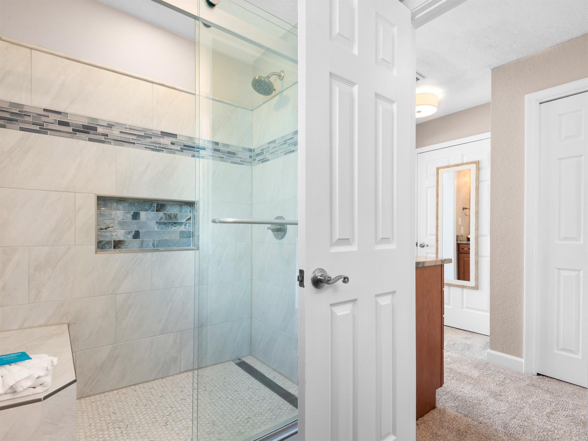 Step into the sleek glass shower with rainfall head and designer tilework for a refreshing start to your day.