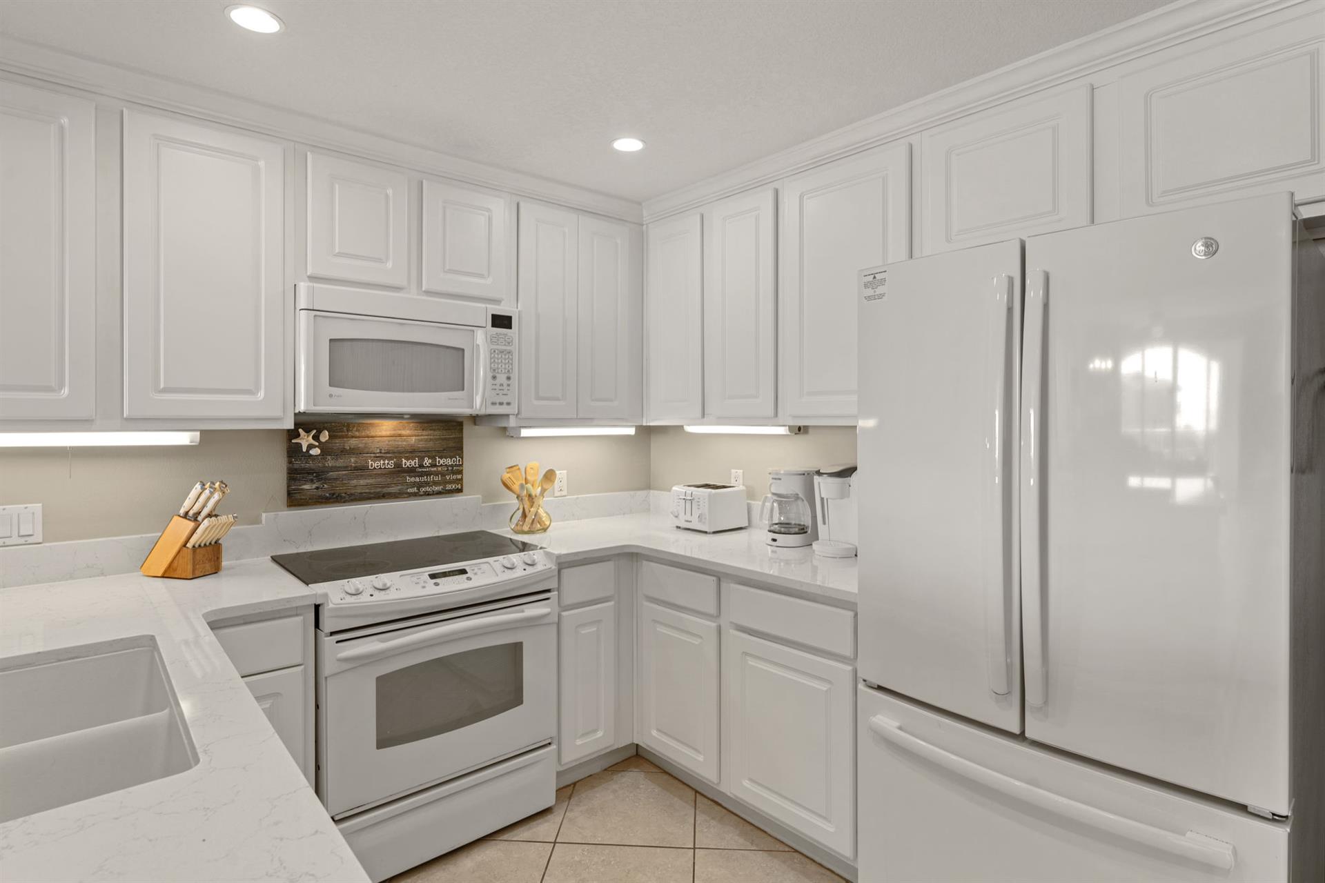 Fully equipped kitchen features white cabinets, granite countertops, and all essential appliances for preparing your favorite meals during your stay.