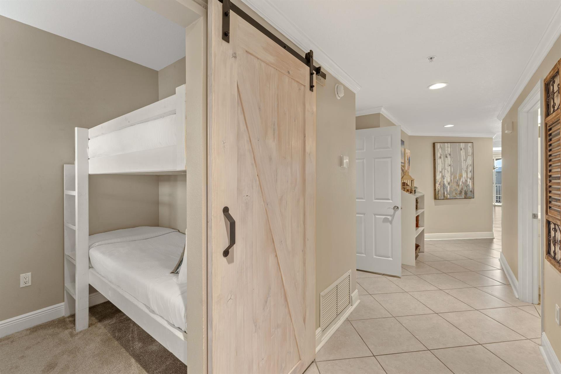 Kids will love this clever bunk bed setup with a rustic barn door for privacy and cozy carpeted floors.