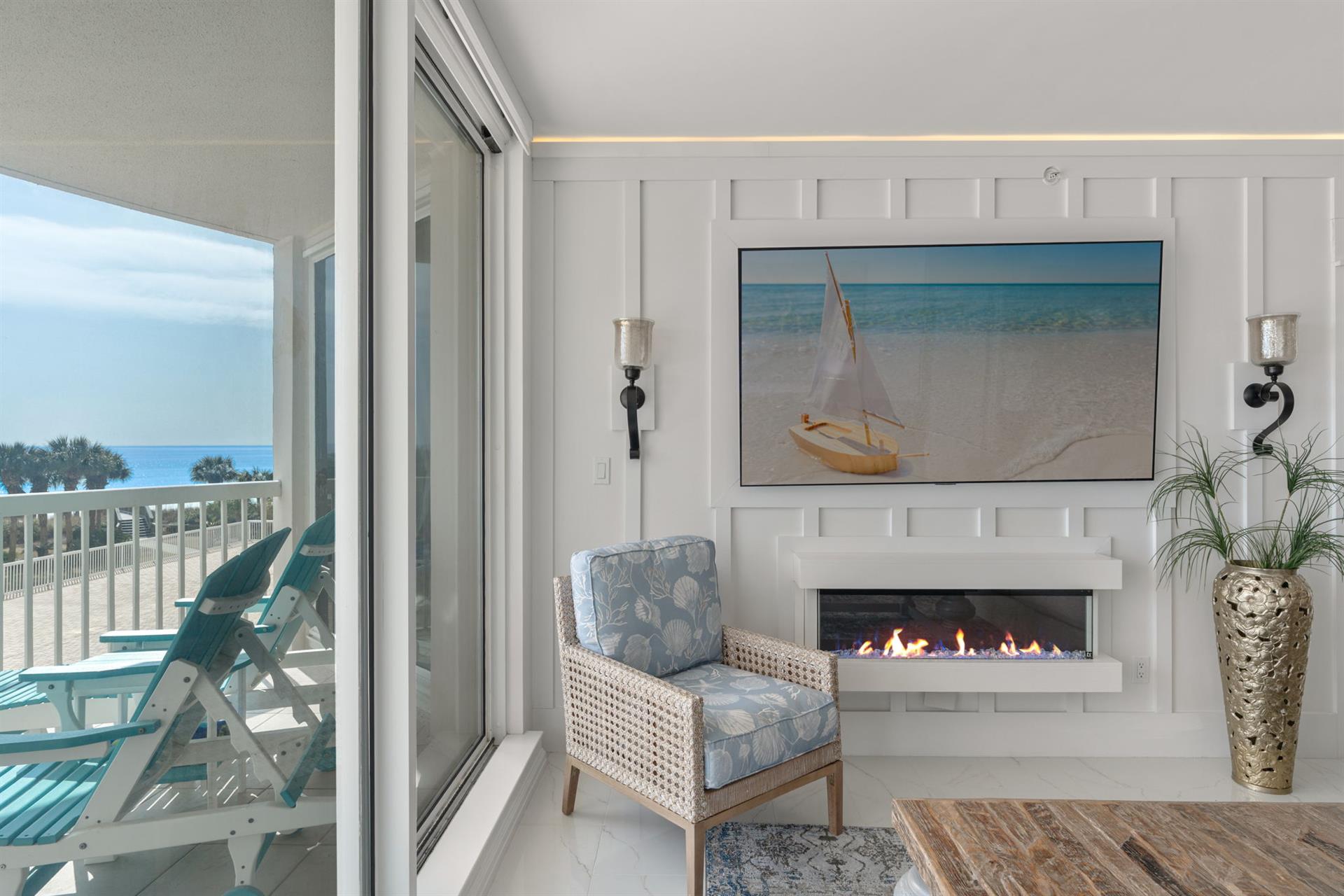 Cozy up by your modern fireplace with stunning sea views through expansive windows, where coastal artwork and elegant furnishings create your perfect beach retreat.