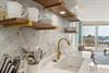 Your stylish kitchen features elegant herringbone backsplash, brass fixtures, and floating shelves with stunning Gulf views.