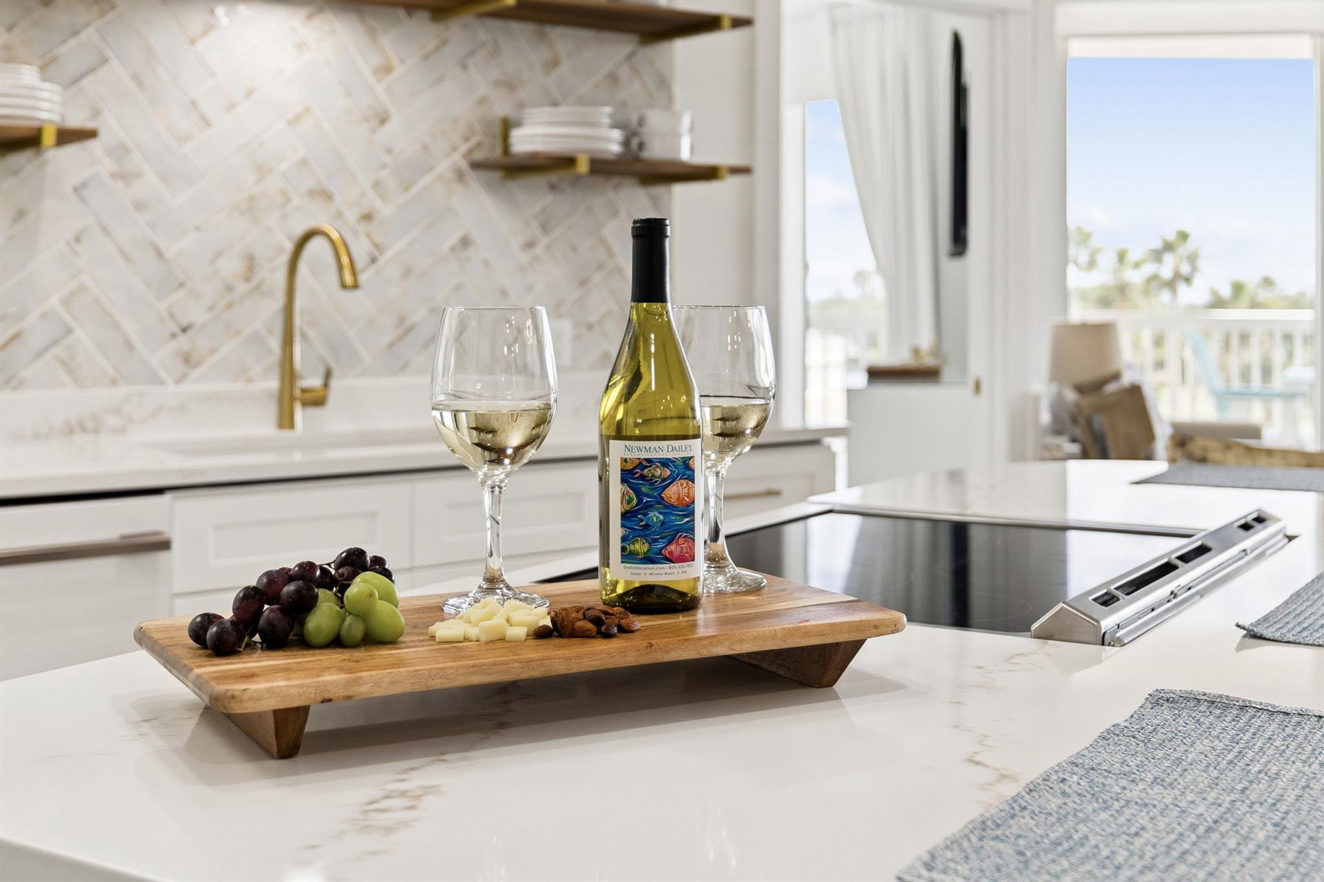 Unwind with wine and cheese in your elegant kitchen, featuring marble counters and gold fixtures for memorable evenings.