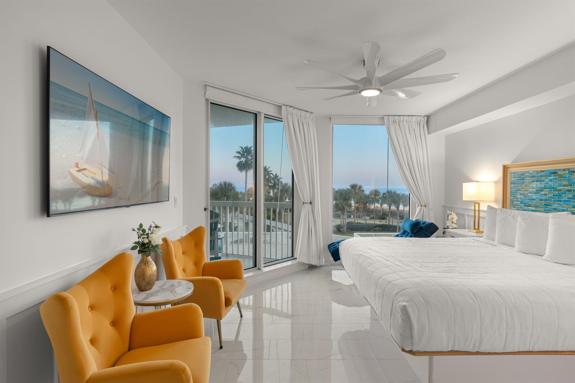 Wake up to tropical views from your bright, modern bedroom featuring plush bedding and stylish seating perfect for morning coffee.