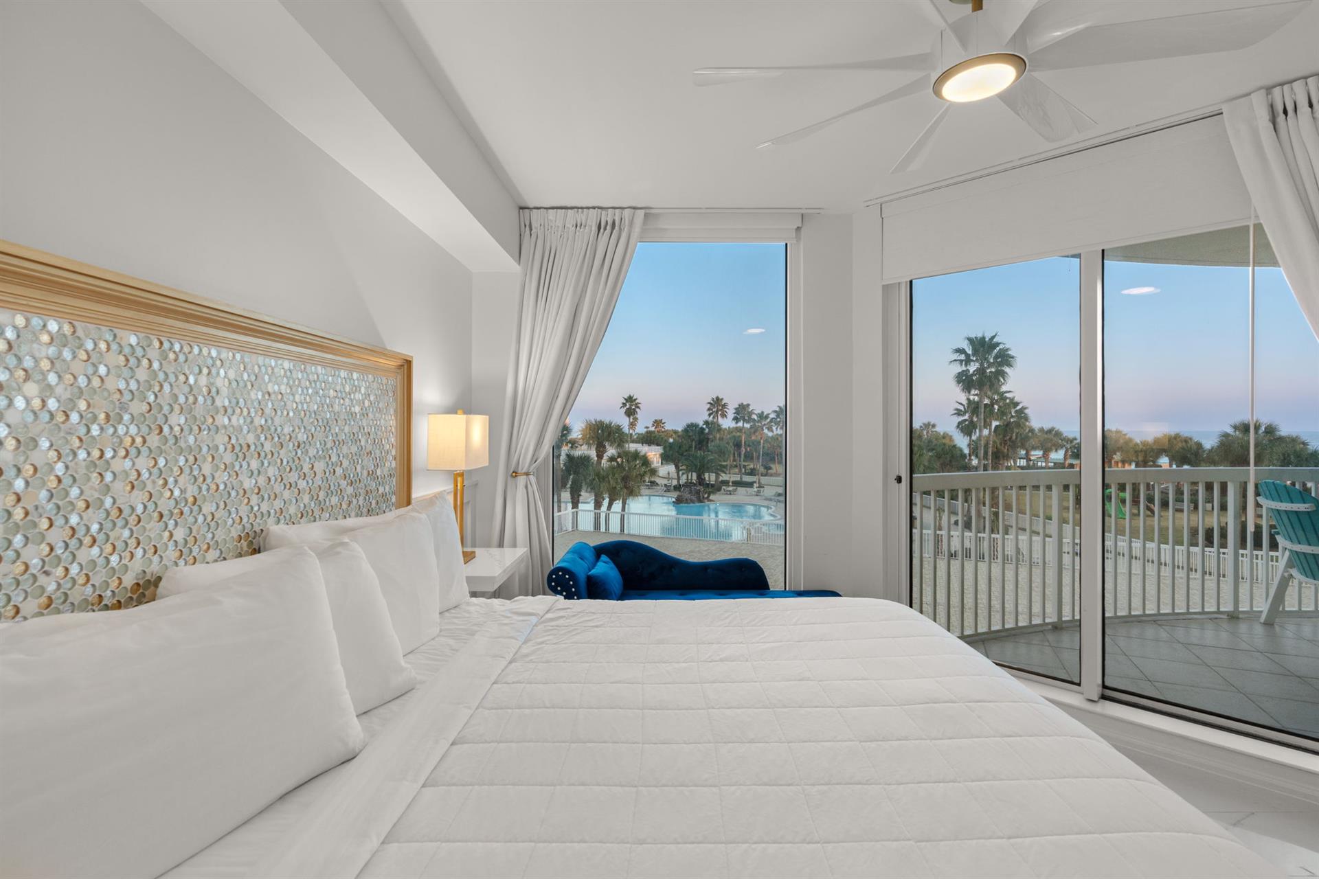 Wake up to stunning pool views from your bright, airy bedroom featuring crisp white linens and tropical palm vistas.
