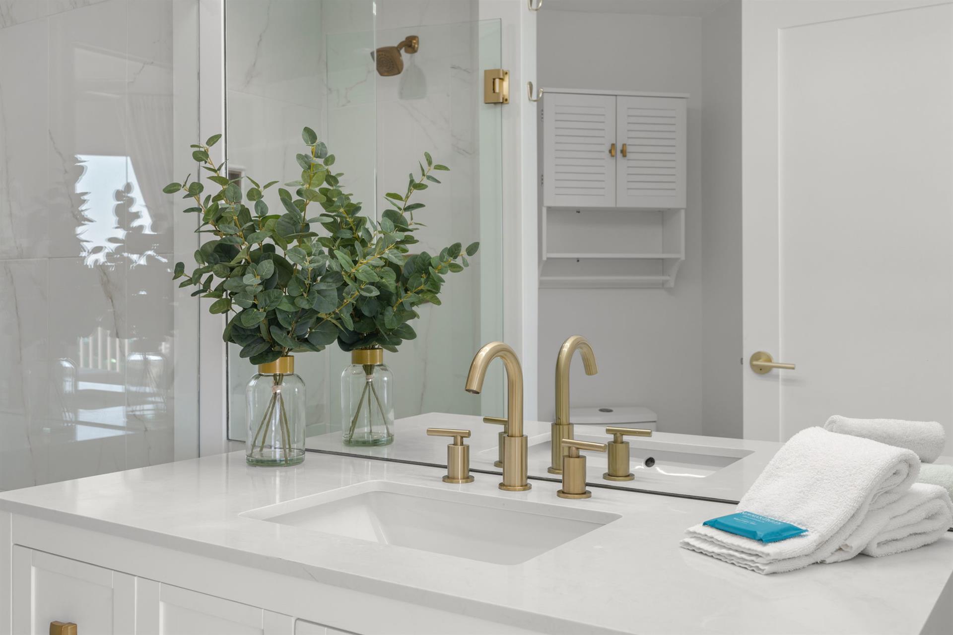 Step into your spalike bathroom featuring elegant gold fixtures, and plush towels ready for your relaxing retreat.