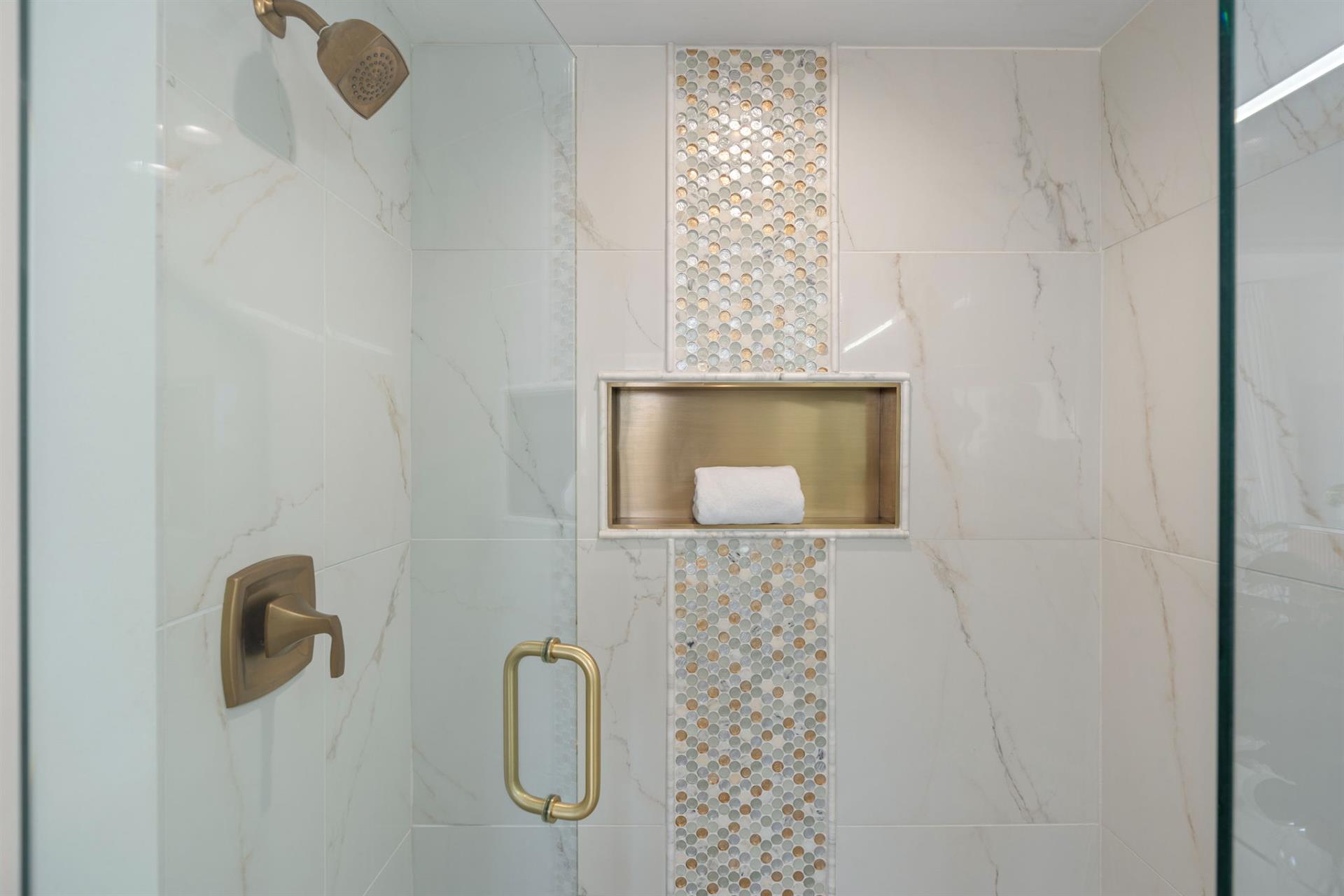 Step into your luxurious marble shower featuring elegant gold fixtures and a convenient builtin niche for your essentials.
