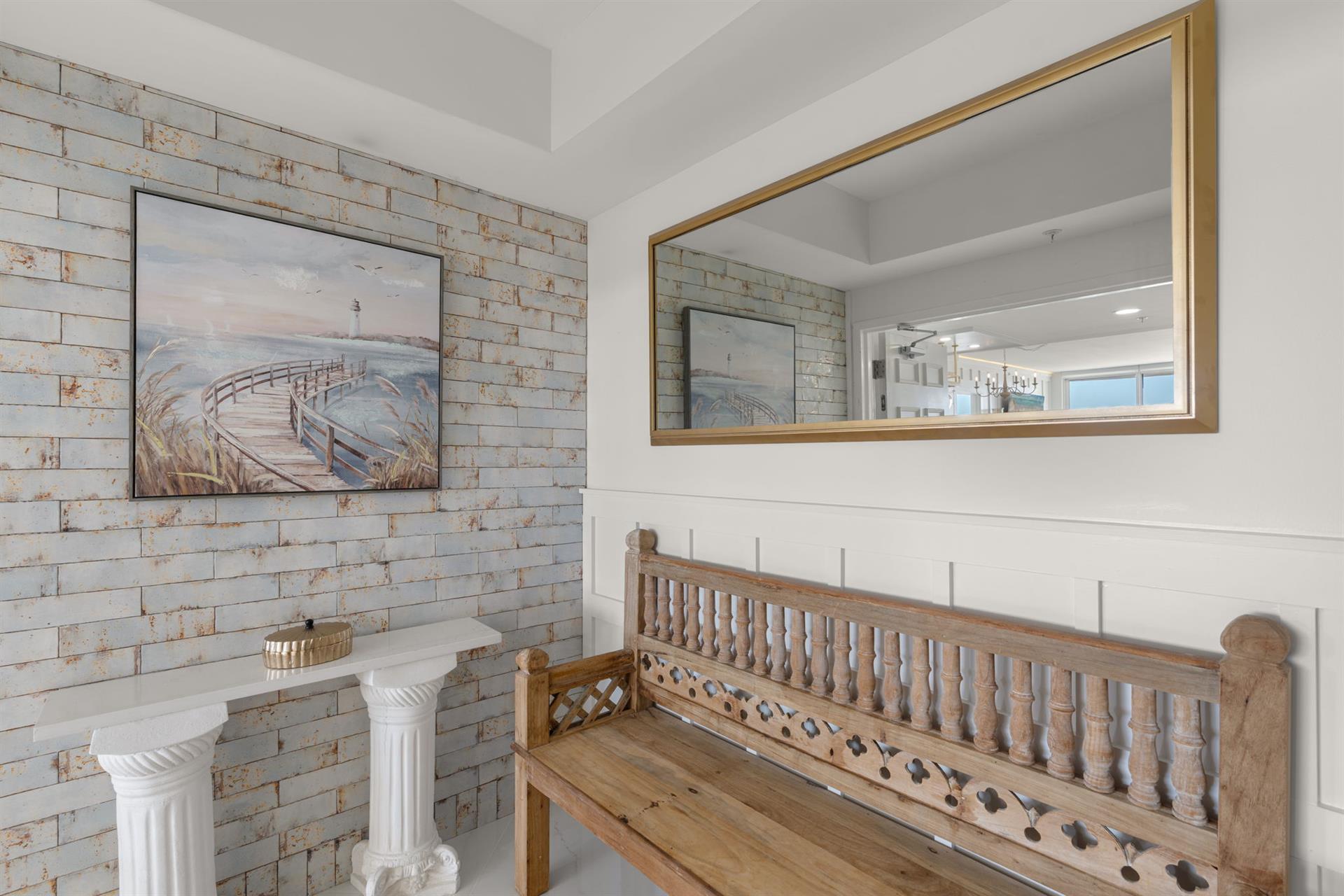 Relax on charming wooden seating while admiring coastal artwork in this inviting space with rustic brick accents.