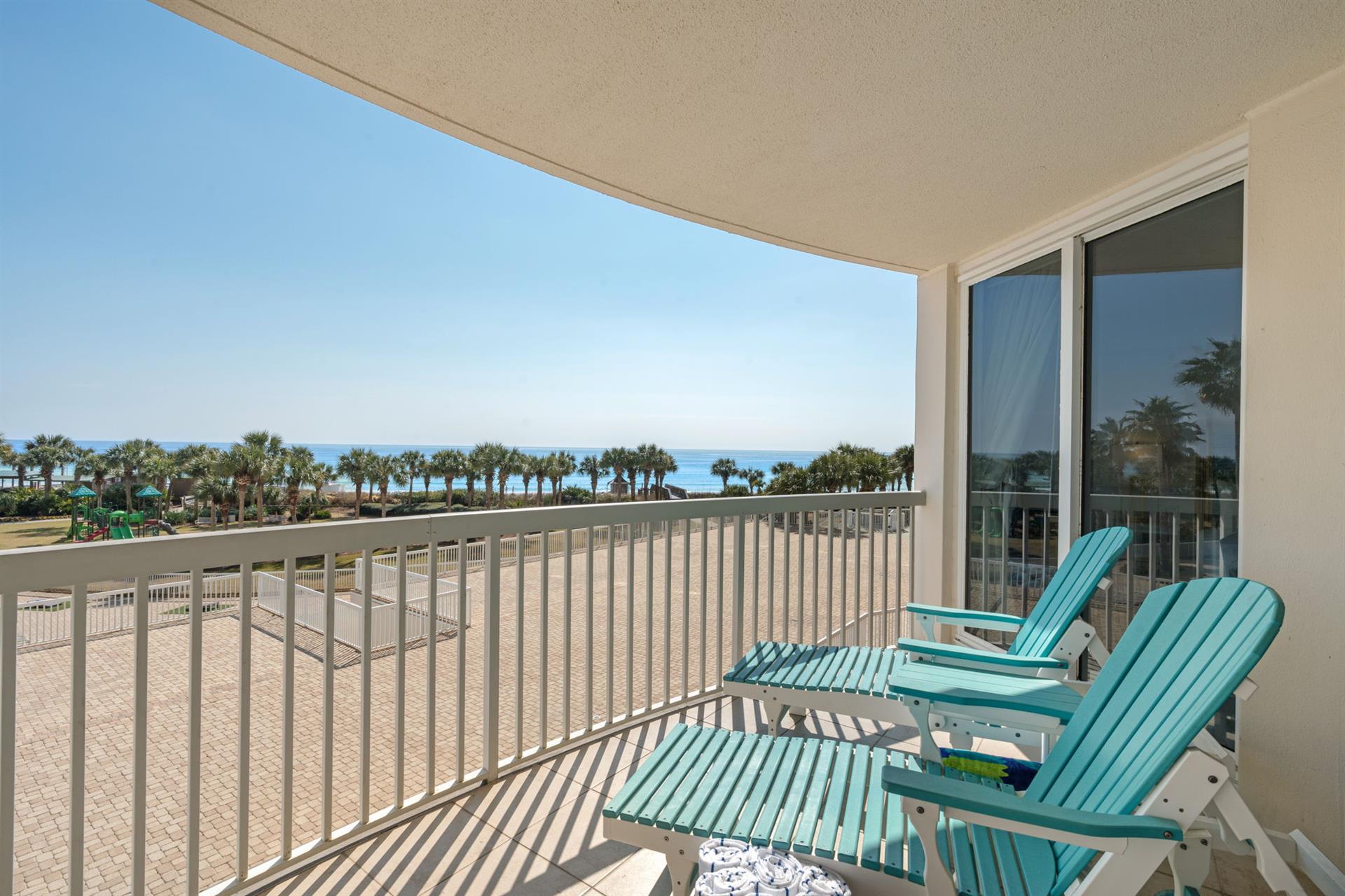 Unwind on your private balcony with stunning ocean views, where turquoise chairs invite you to relax while palm trees sway in the coastal breeze.