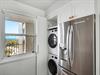 Your bright laundry nook features stacked washer and dryer with crisp white cabinetry