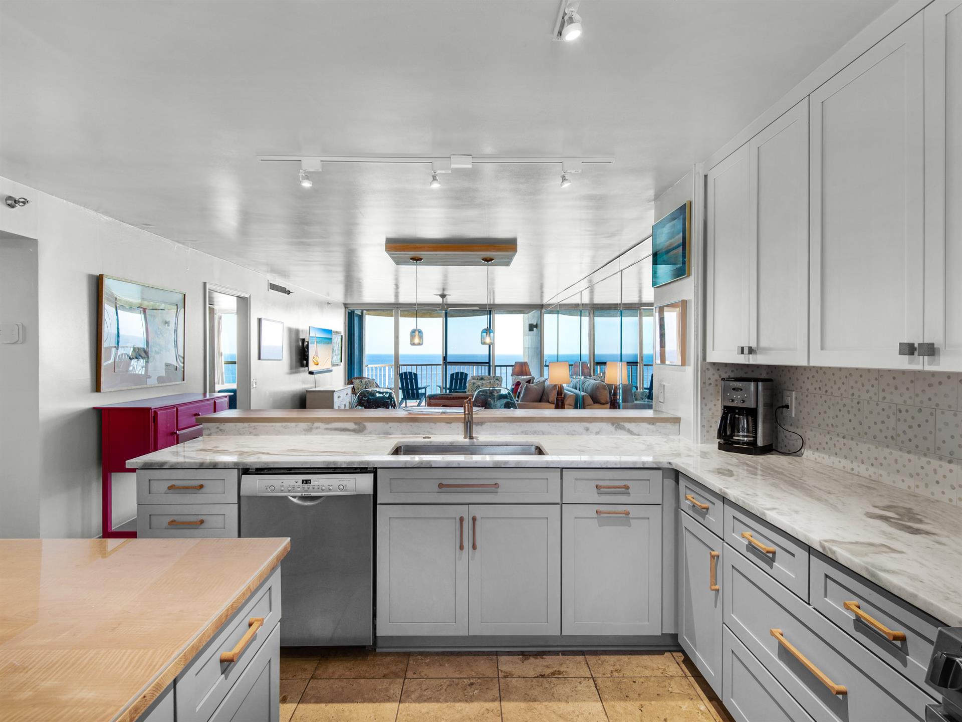 Cook with stunning ocean views in this sleek modern kitchen featuring marble countertops, stainless appliances, and panoramic windows.