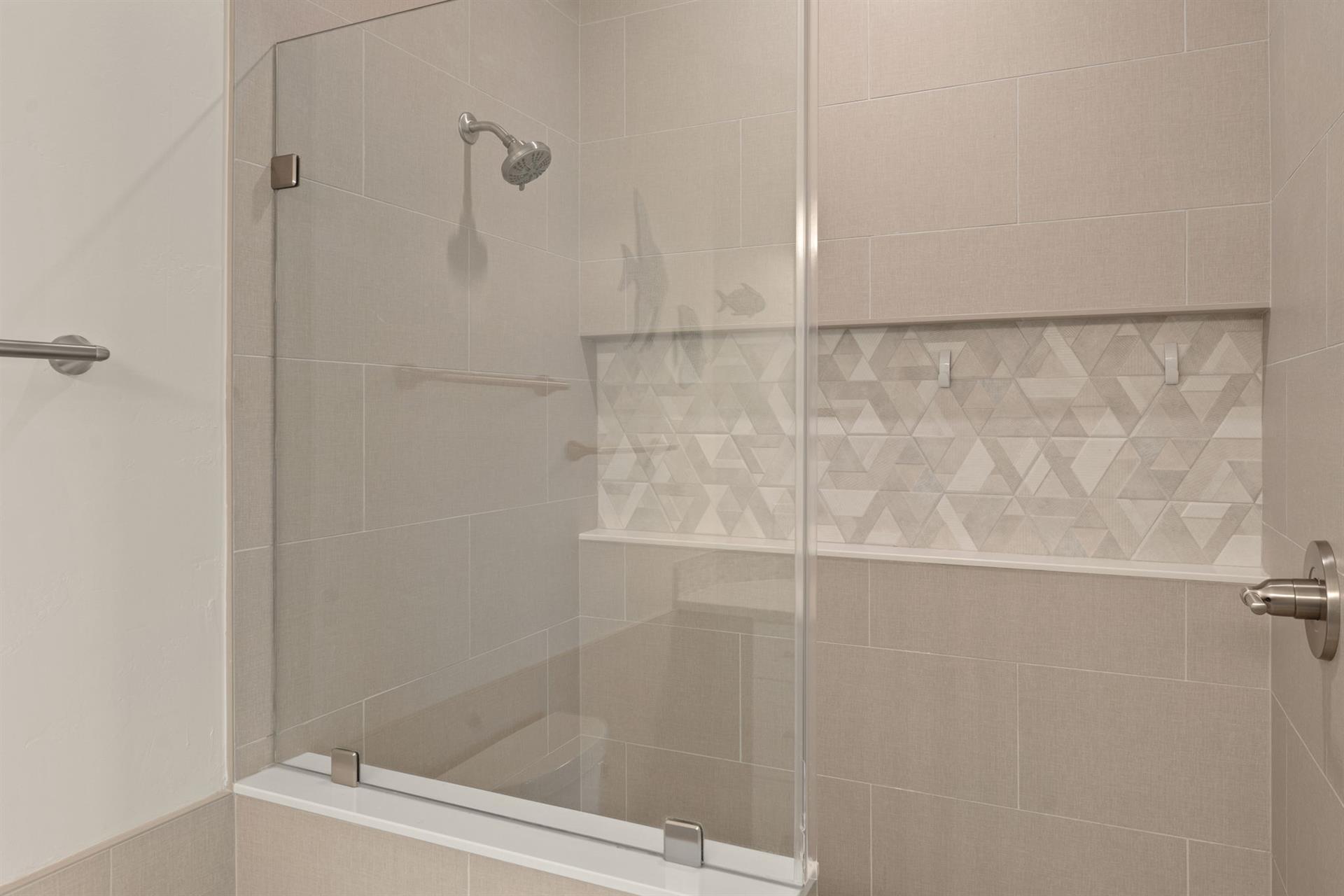 Step into your private spalike shower with elegant glass doors, designer tiling, and a builtin bench for ultimate relaxation.
