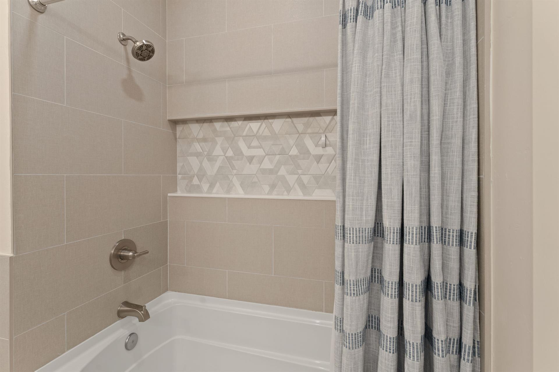 Slip into your private showertub combo featuring elegant tiled walls and a decorative mosaic niche for your toiletries.