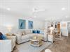 Relax in your bright, coastalinspired living space featuring plush sectional seating, charming heron artwork, and an open layout flowing into the dining area.