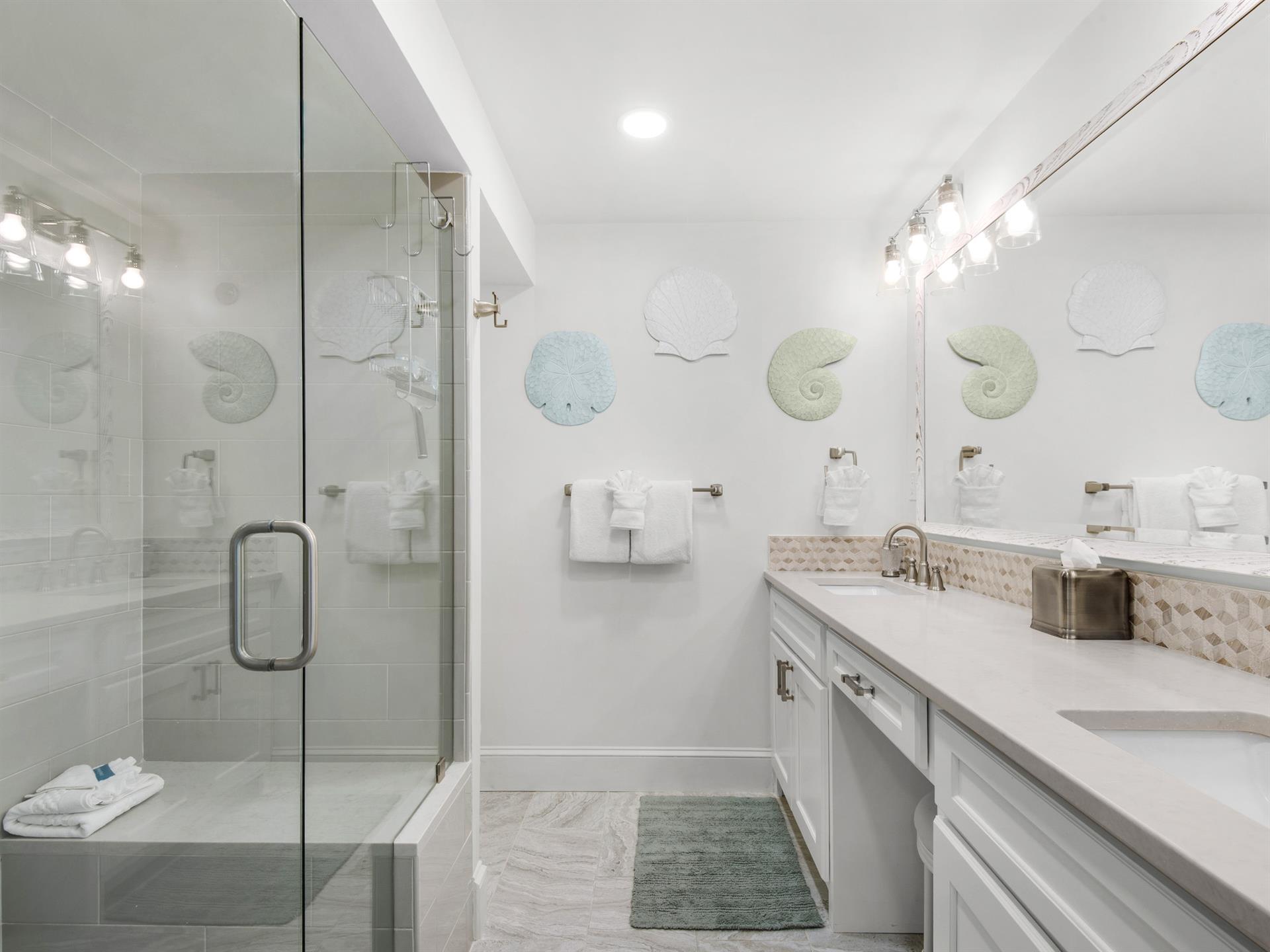Bathroom 1  Unwind in your coastalinspired bathroom with glassenclosed shower, elegant dual vanity, and charming seathemed touches.