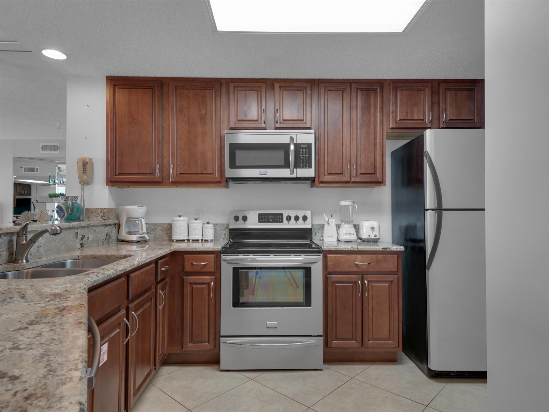 Your fully equipped kitchen features rich wood cabinets, granite counters, and modern appliances, perfect for preparing meals during your stay.
