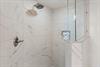 Step into your luxurious marbletiled shower with rainfall showerhead and builtin amenities niche for a spalike experience.