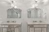 Your luxurious bathroom features dual vanities with Venetian mirrors and sparkling pendant lights, creating an elegant space for your morning routine.