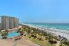 Beachfront resort with swimming pool and pristine white sand beach stretching along emerald Gulf waters.