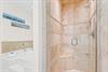 Unwind in your luxurious marble bathroom featuring a rainfall shower and soaking tub, where coastal artwork adds peaceful touches to your private retreat.