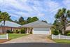 Charming singlestory home with metal roof nestled among palm trees in peaceful residential neighborhood.