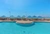 Sparkling pool with beachfront access featuring turquoise umbrellas and lounge chairs overlooking pristine sandy shores.