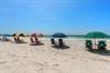 Sandy beach with colorful umbrellas and chairs set up along the pristine waterfront.