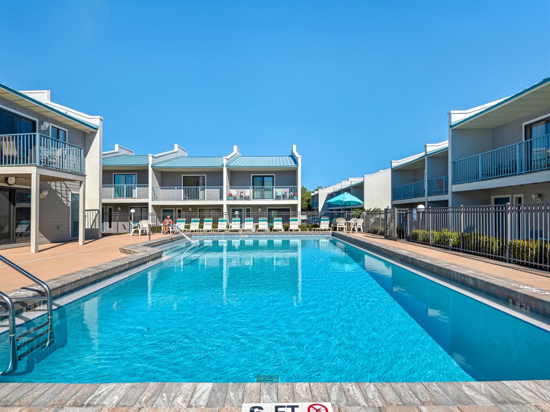Crystalclear pool surrounded by comfortable accommodations under brilliant blue skies, creating the perfect backdrop for your relaxing getaway.