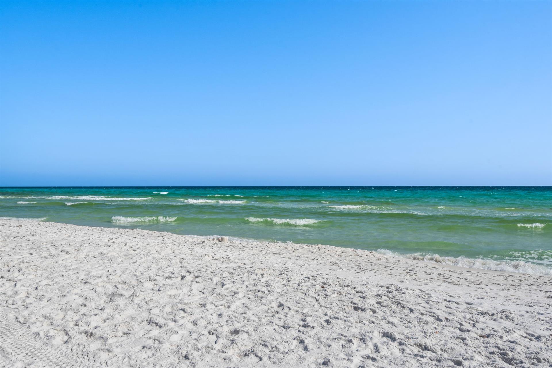 White sand beach with crystalclear turquoise waters and gentle waves under a bright blue sky