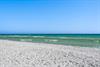 White sand beach with crystalclear turquoise waters and gentle waves under a bright blue sky