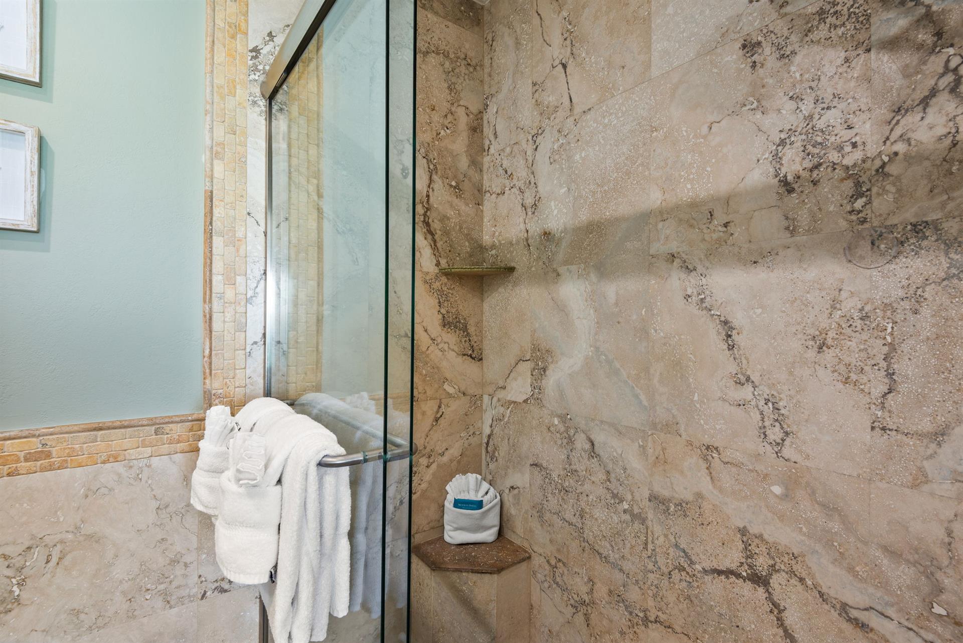 Step into the walkin shower with luxurious marble walls and fresh towels waiting for you.