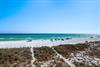 Pristine white sand beach with turquoise waters stretches endlessly under brilliant blue skies, where beachgoers relax beneath colorful umbrellas.