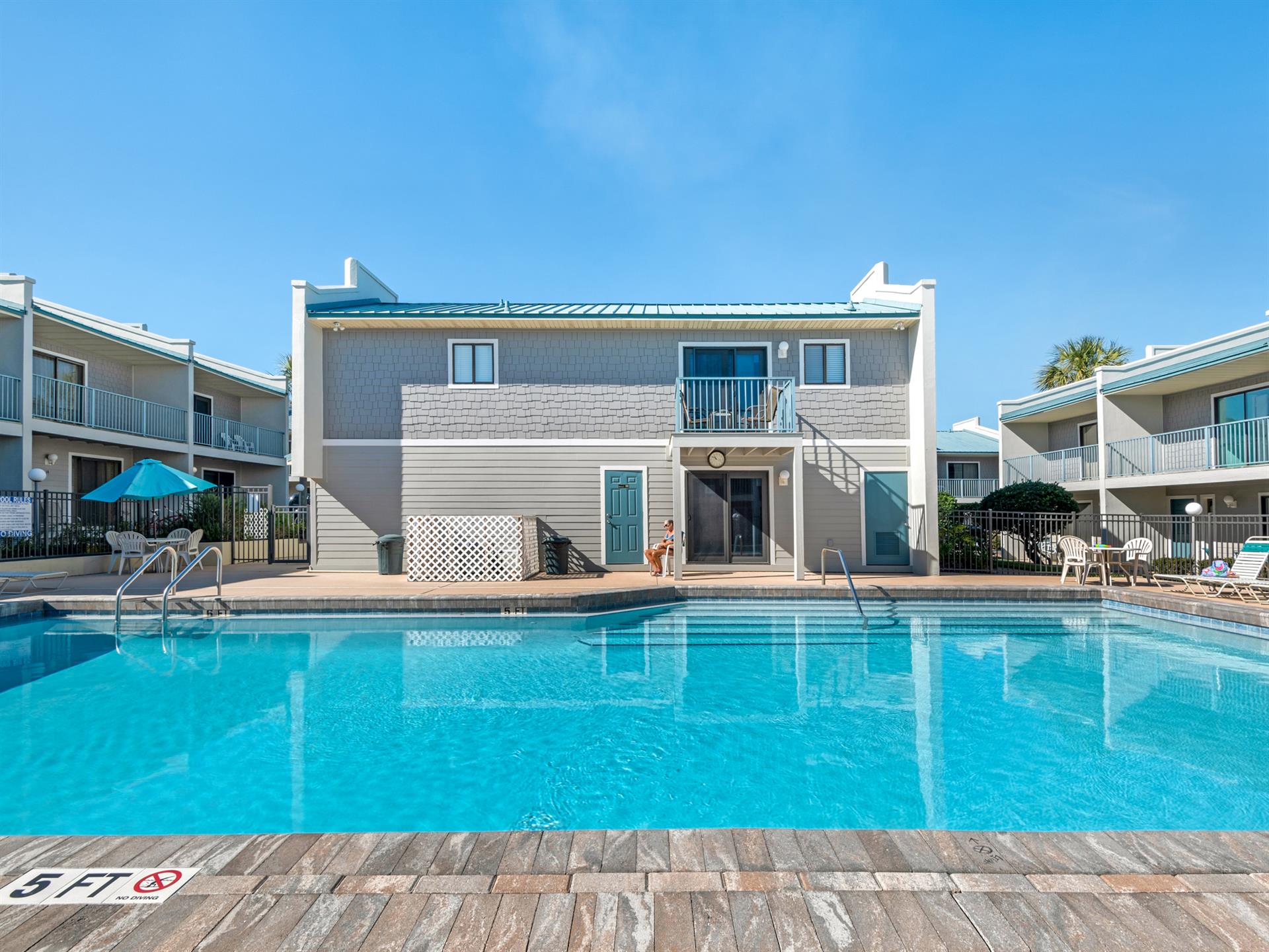 Beachside resort featuring pristine pool, modern accommodations, and tropical Florida atmosphere under clear blue skies.