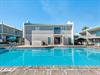 Beachside resort featuring pristine pool, modern accommodations, and tropical Florida atmosphere under clear blue skies.